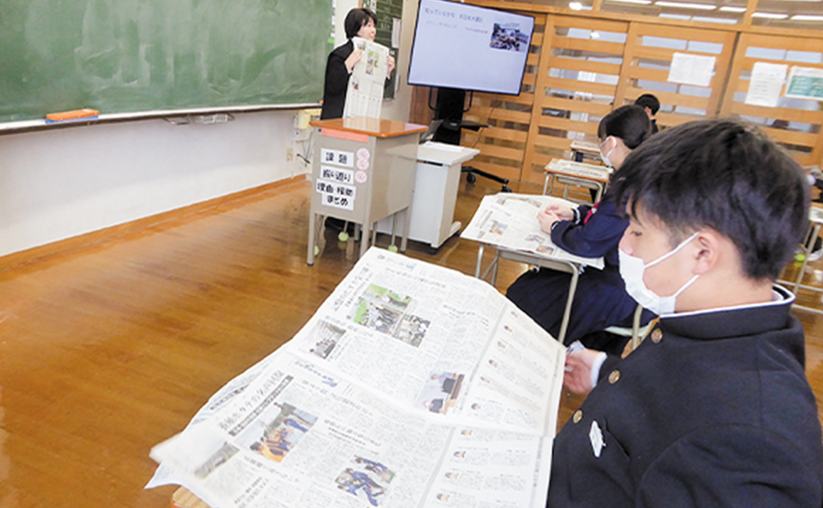 「震災伝承新聞」を読む門前中の生徒たち